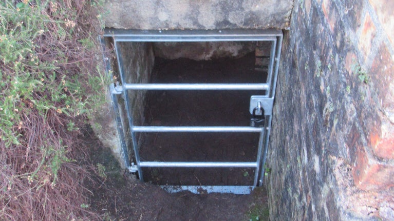 Concrete wartime bunker with metal grill over entrance.